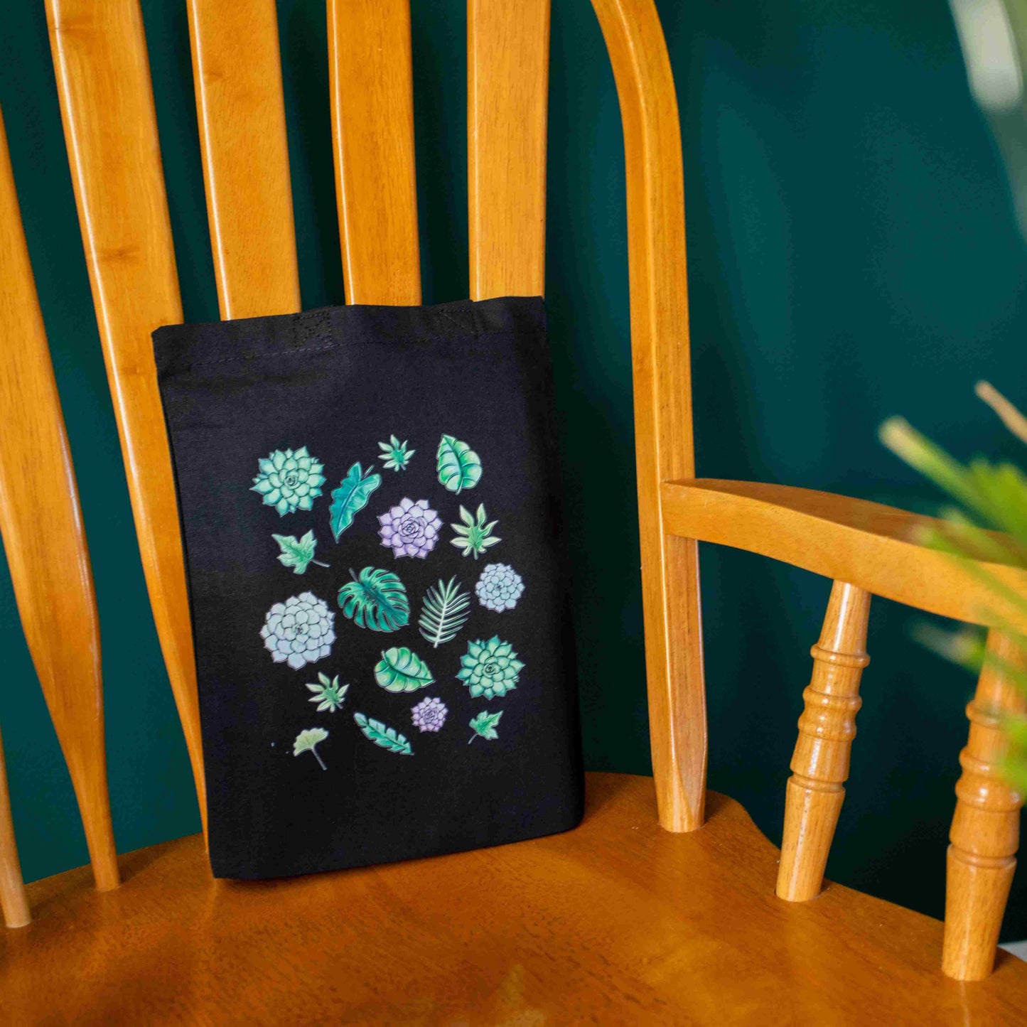 Black tote bag on a wooden chair with image of succulents